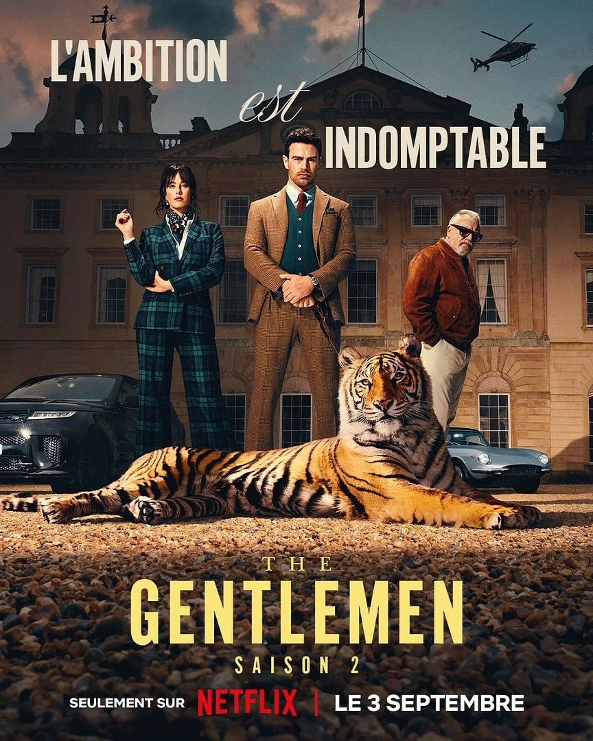 Affiche de la saison 2 de the gentlemen montrant Theo James,  Kaya Scodelario et Ray Winstone en costumes devant un palais avec un tigre au premier plan